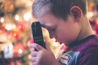 young boy praying with Bible