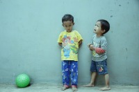 2 small boys, one has caused the 2nd to cry, ball solic background